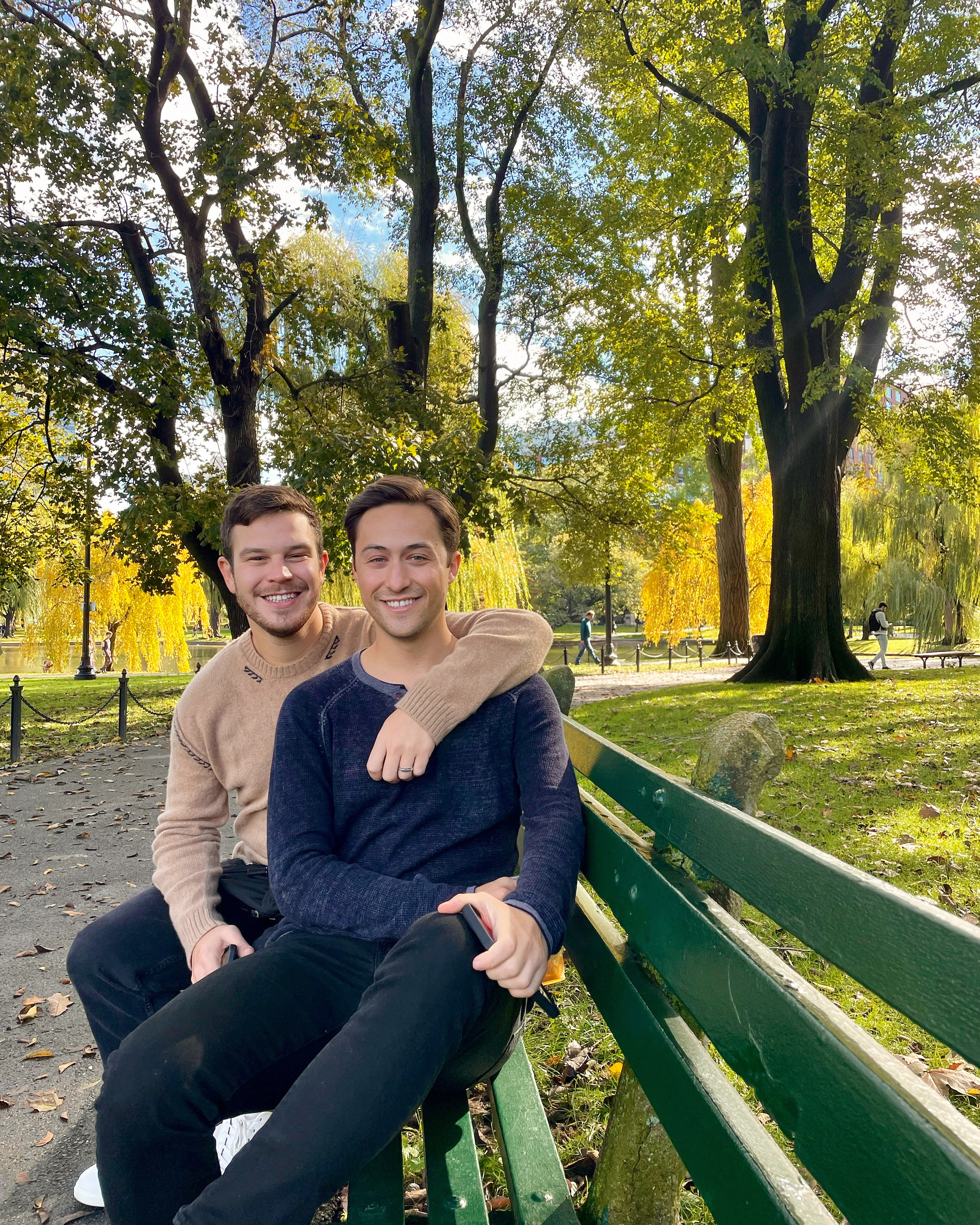 Phil and Zack sitting together on a park bench in the fall